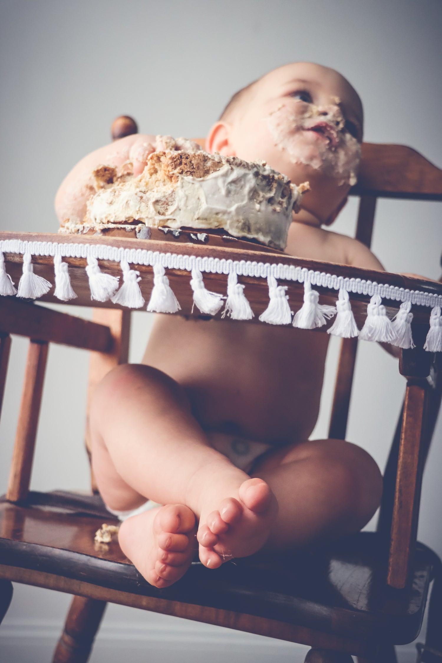 A baby in a high chair with a smashed birthday cake