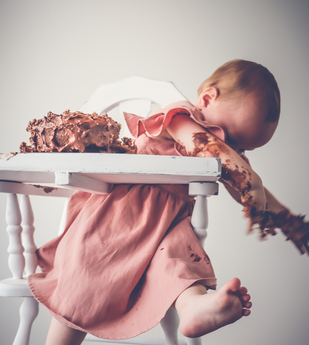 A baby in a high chair smashing a cake